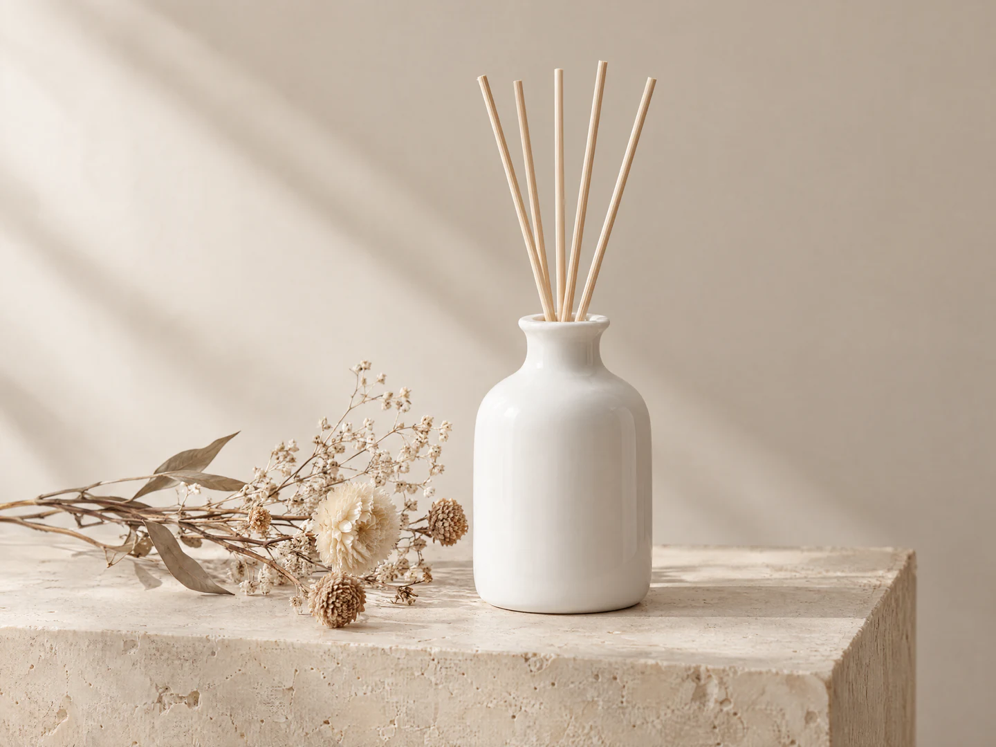 Foto de produto gerada por IA com um difusor branco de cerâmica e flores secas sobre um bloco de pedra bege, com luz lateral suave projetando sombras na parede